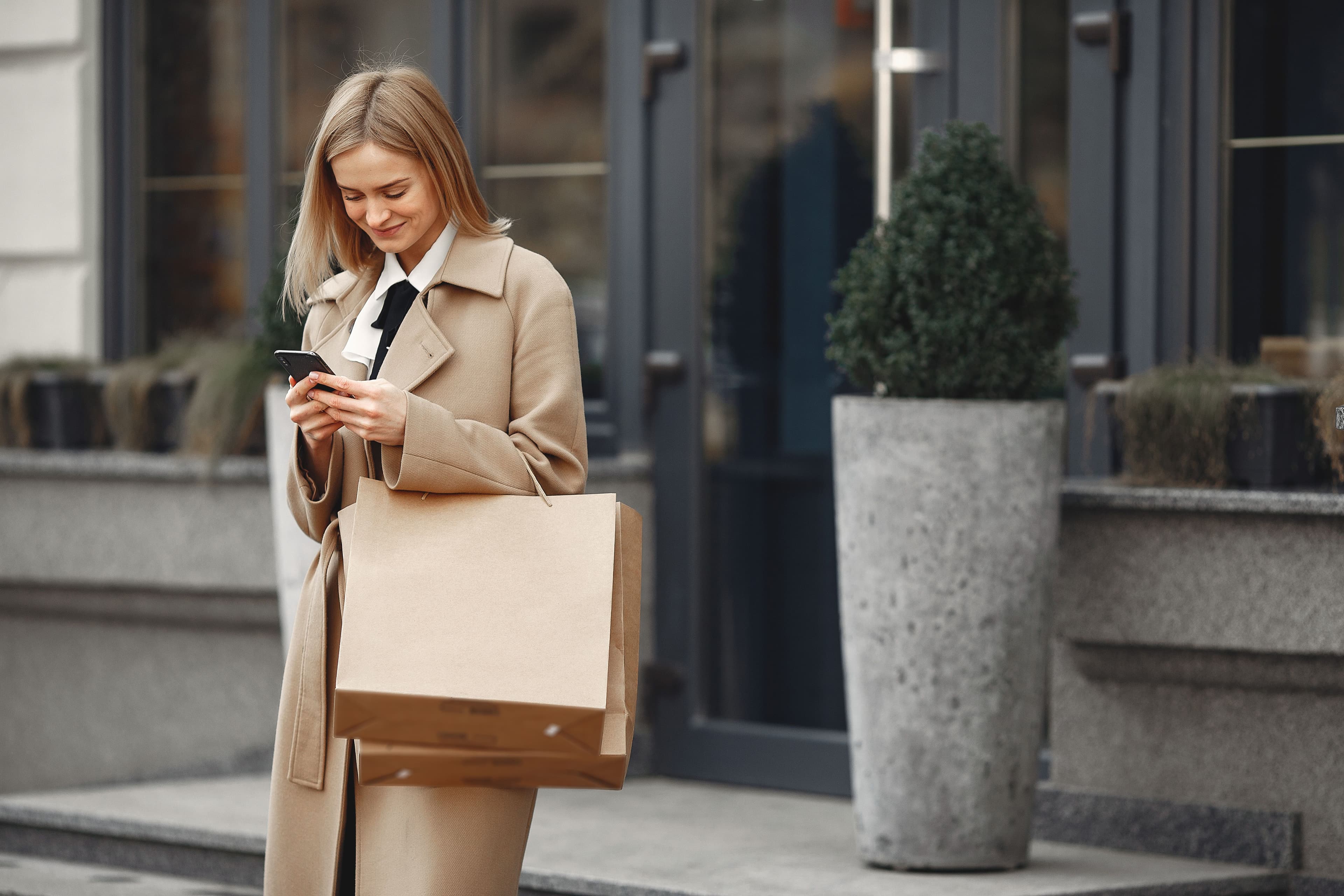 A newly arrived international patient checking her phone outside her hotel, bags in hand